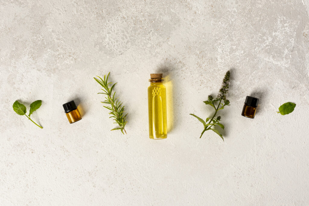 flacon d'huile essentielles avec herbes aromatiques sur fond clair